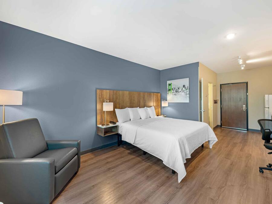 A hotel room with a bed, a desk, a chair, and a nightstand.