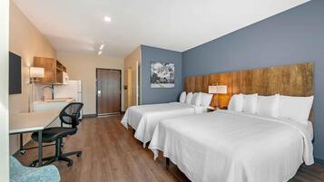 A hotel room with two beds, a desk, a chair, and a large wooden headboard.