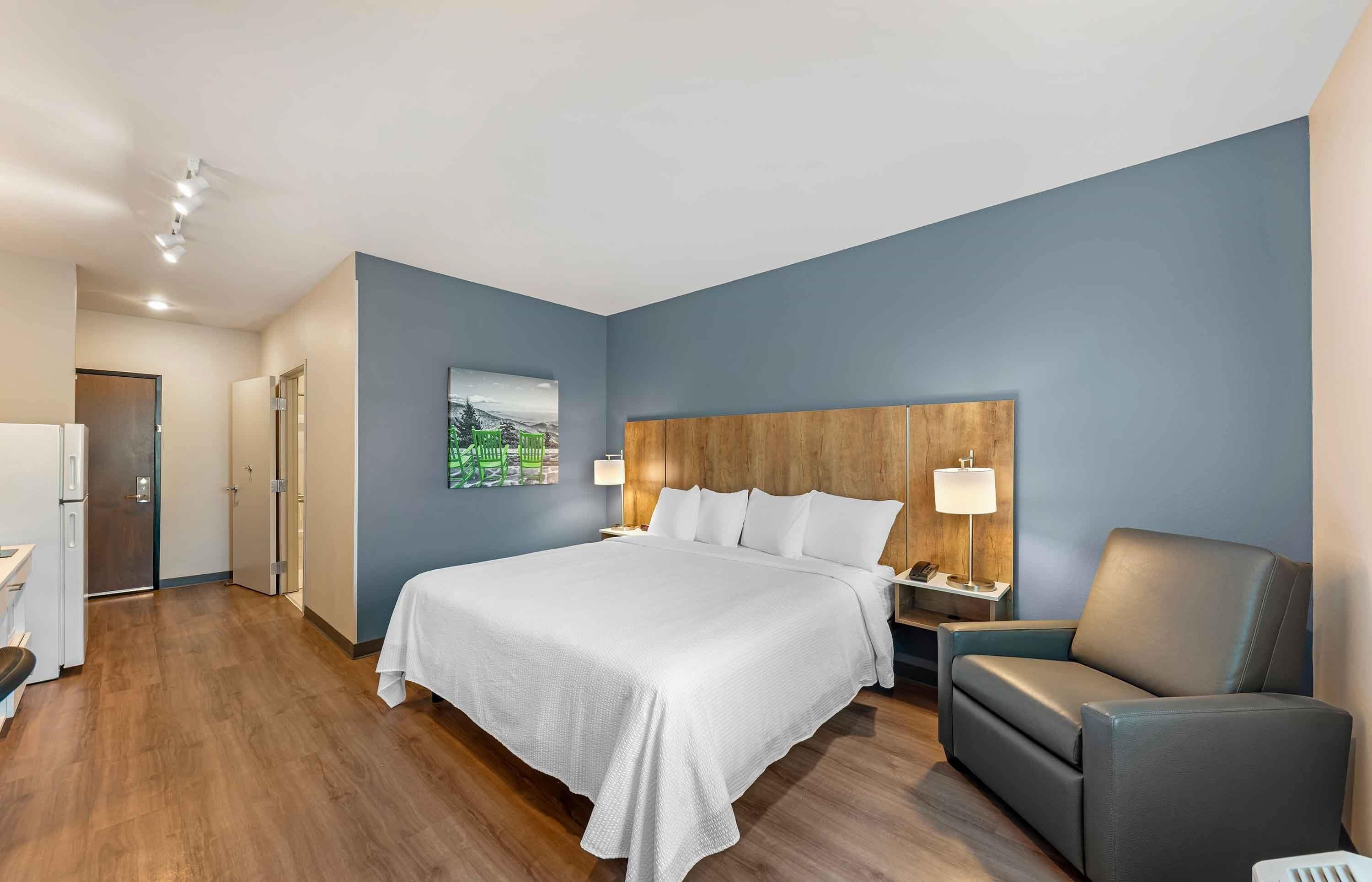 Una habitación de hotel con una cama grande, un cabecero de madera, una mesita de noche, un escritorio y una silla.