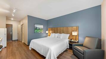 A hotel room with a large bed, a wooden headboard, a nightstand, a desk, and a chair.