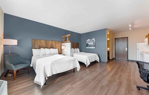 Une chambre d’hôtel avec deux lits, un bureau, une chaise et une porte.