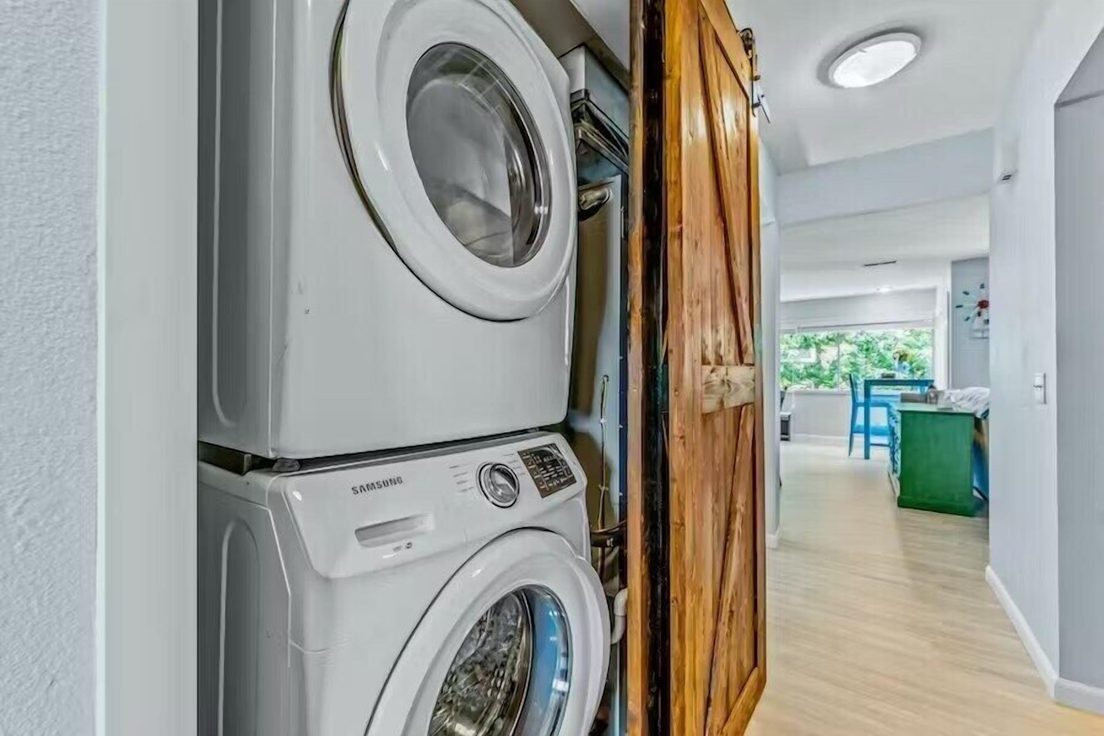 Een wasruimte met gestapelde wasmachines en een houten deur.