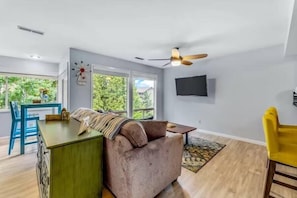 Un salon moderne avec un canapé, une table à manger et un téléviseur fixé au mur.
