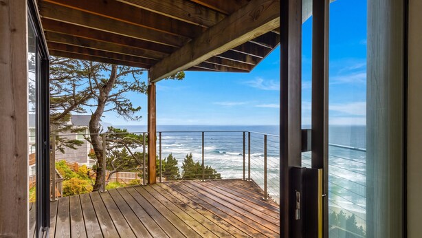 Eine Holzterrasse mit Blick auf das Meer und einen Baum.
