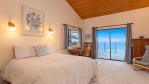 Ein Schlafzimmer mit Bett, Schreibtisch, Stuhl, Bücherregal und Meerblick.