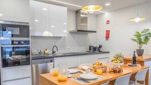 A modern kitchen with stainless steel appliances, a wooden dining table, and a breakfast setup. - A View to Paradise – Spectacular Sea & Bay Views (Funchal)