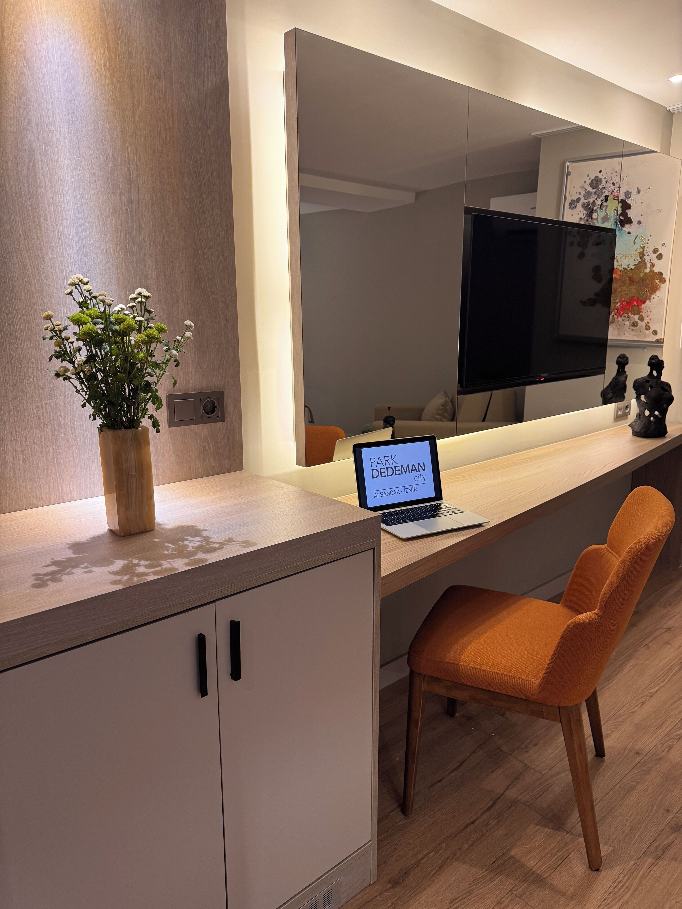 Un espacio de oficina moderno con un escritorio de madera, una computadora portátil, una silla y un florero con flores.