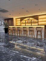 Una zona de bar con taburetes de madera y suelo de mármol.