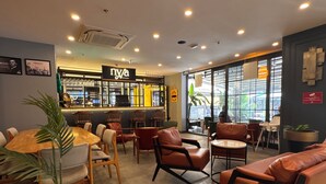 Un café moderne avec un intérieur élégant, un bar, des espaces aménagés pour s’asseoir et de grandes fenêtres qui laissent entrer la lumière naturelle.