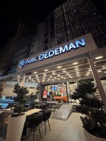 Un edificio con un letrero que dice "PARK DEDEMAN" y un área exterior con mesas y sillas.