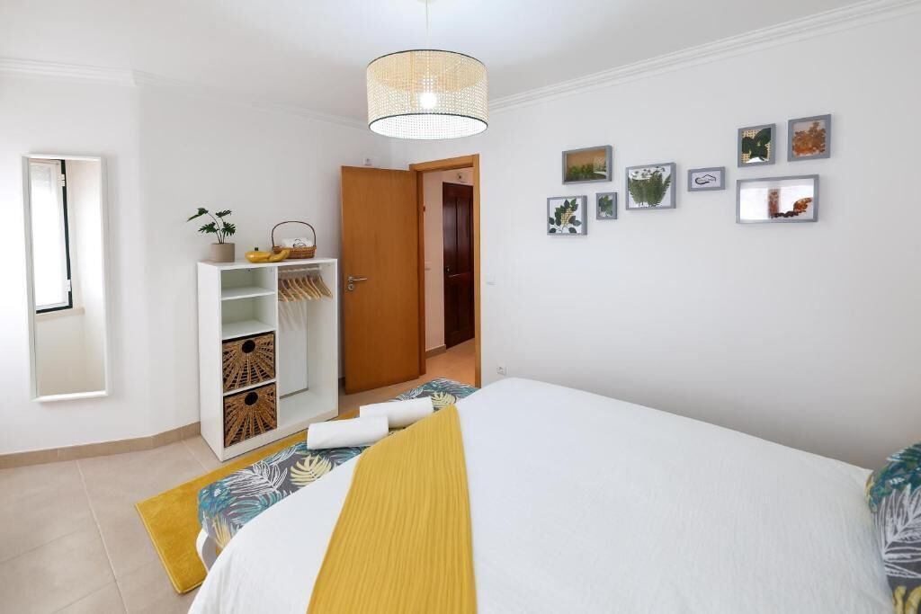 Ein Schlafzimmer mit Bett, Kleiderschrank, Spiegel und einer Tür zu einem weiteren Raum.