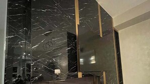 Een moderne woonkamer met een zwarte marmeren open haard, een flatscreen televisie aan de muur en een minimalistisch design.