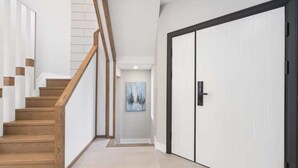 Een modern interieur met een houten trap, een witte deur en een schilderij aan de muur.