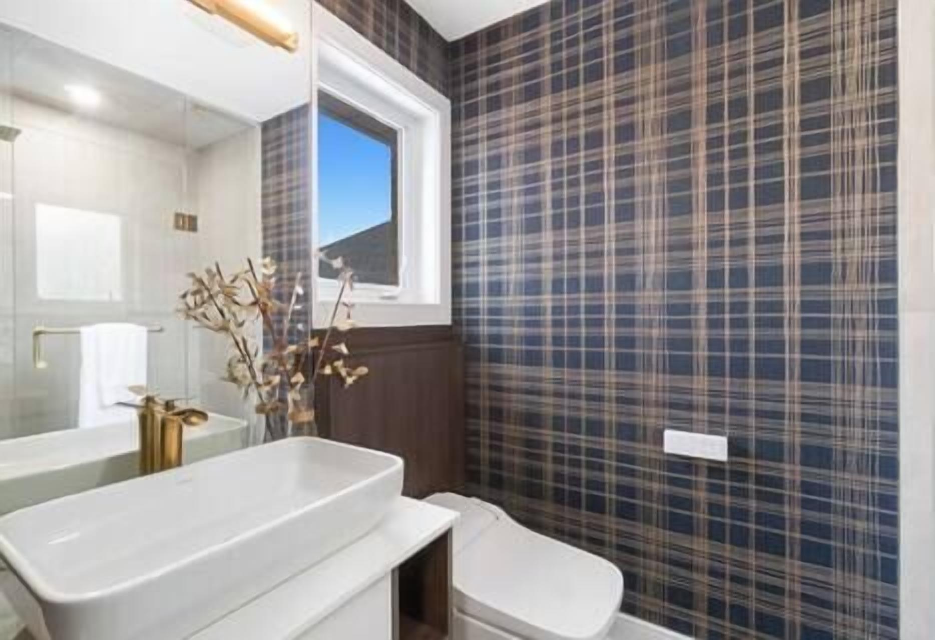 Een badkamer met een wit wastafel, toilet en raam.