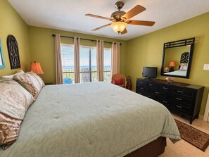 A bedroom with a bed, a ceiling fan, a television, a dresser, and a window with curtains. - Saida III Condos - S3706 (South Padre Island)