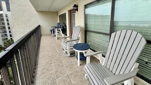 A balcony with outdoor seating, including chairs and a table, and a view of the cityscape. - Saida III Condos - S3706 (South Padre Island)