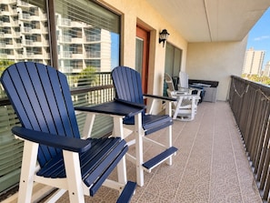 A balcony with two Adirondack chairs, a small table, and a potted plant. - Saida III Condos - S3706 (South Padre Island)