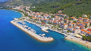Ett flygbildsbild av en kuststad med en småbåtshamn, bostadshus och en strand.