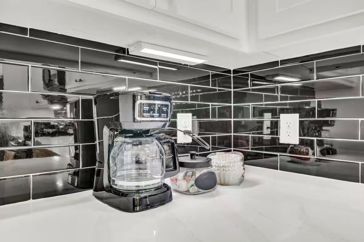 A modern kitchen with a coffee maker, a glass carafe, and a white countertop.