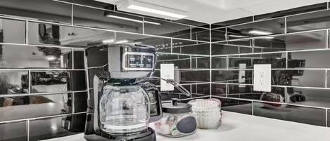 A modern kitchen with a coffee maker, a glass carafe, and a white countertop.