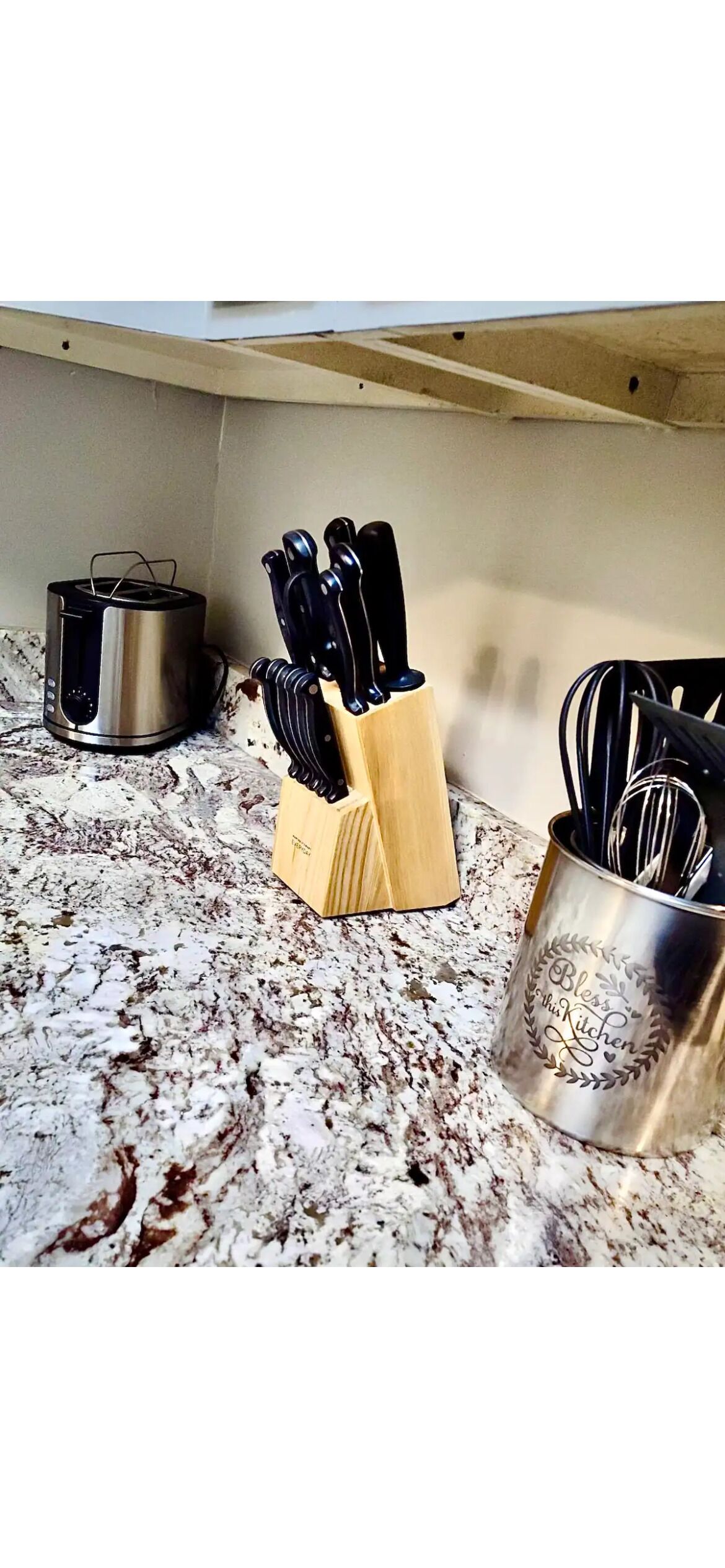 Un plan de travail de cuisine avec un grille-pain, un bloc à couteaux et un porte-ustensiles.