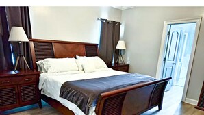 Un lit bien fait, avec une tête de lit en bois, deux tables de chevet avec des lampes et un banc en bois au pied du lit.