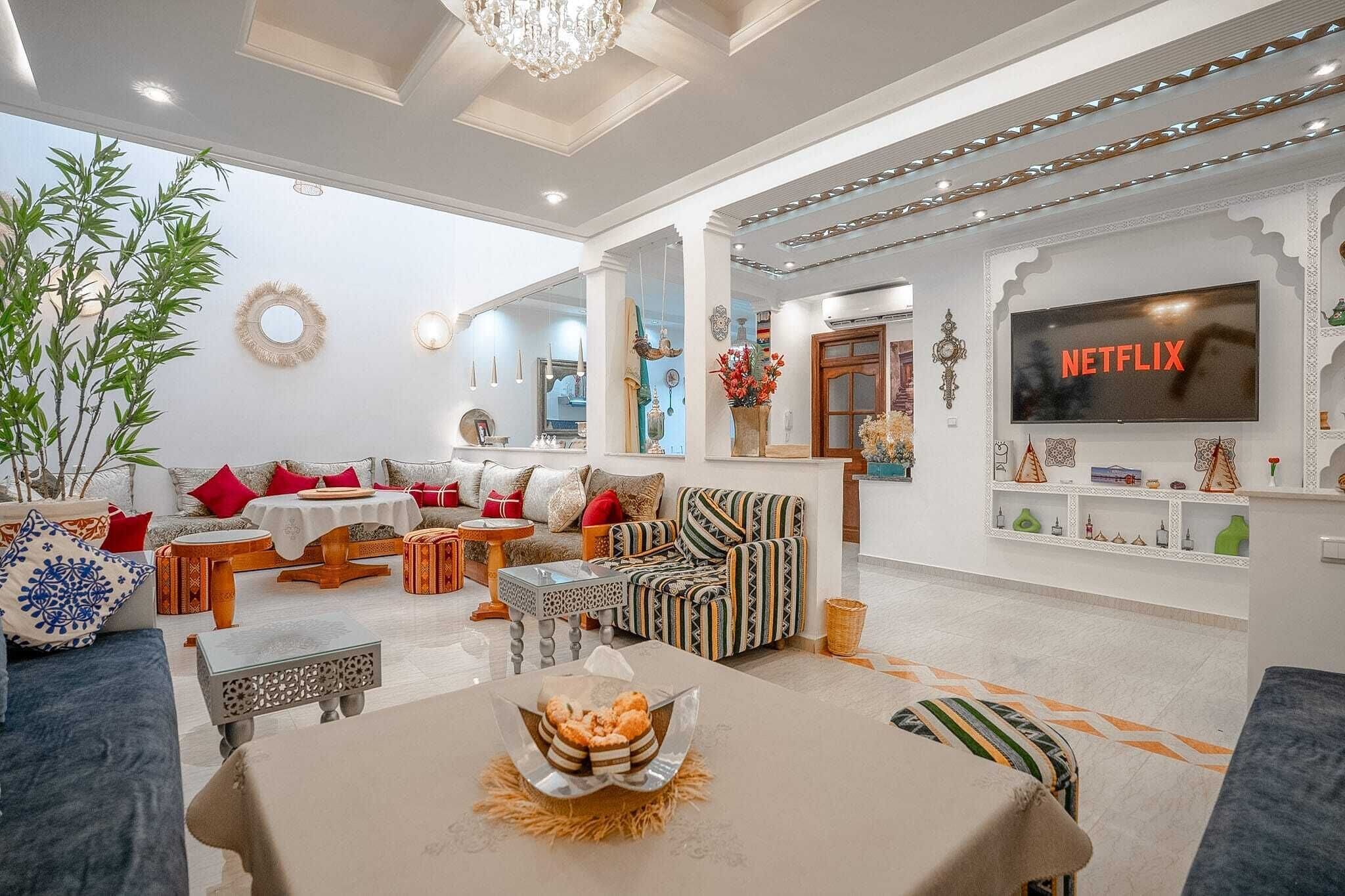 A modern living room with a sofa set, a coffee table, and a television displaying 'NETFLIX'.