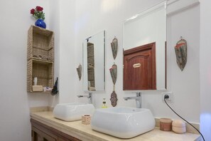 Ein Badezimmer mit zwei Waschbecken, einem Spiegel und dekorativen Wandelementen.