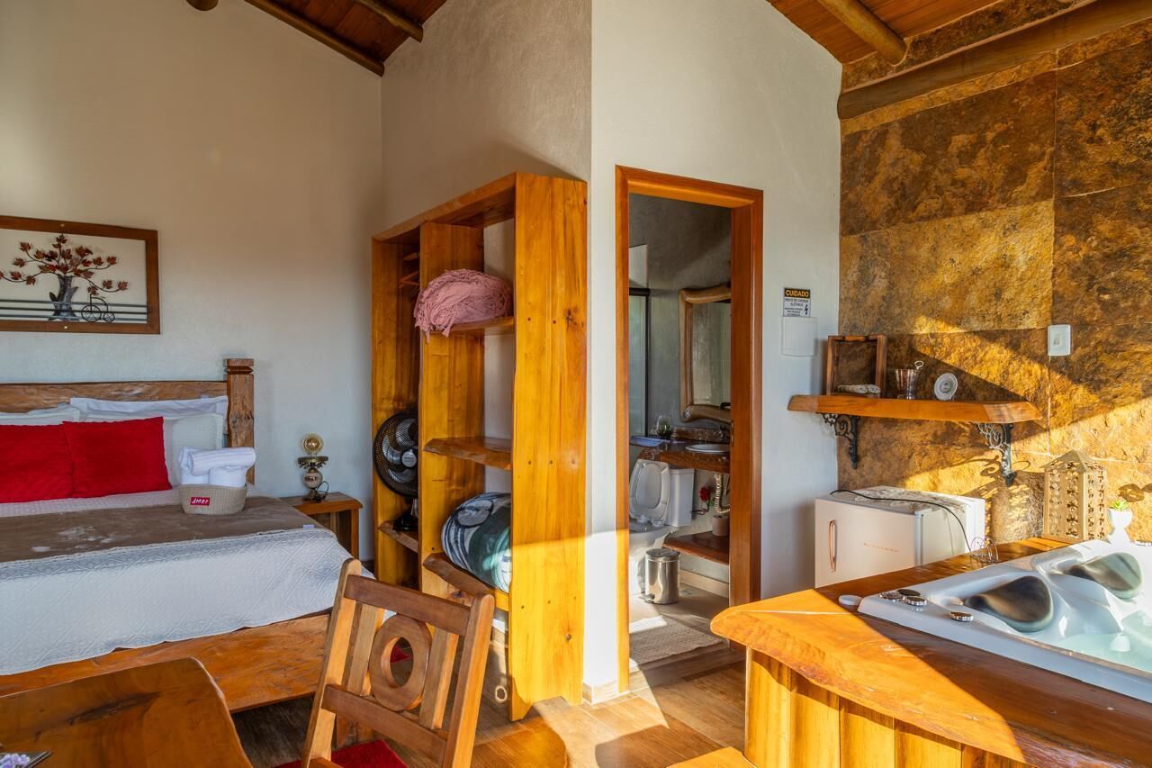 A cozy room with a bed, wooden furniture, a small table with a hot tub, and a stone wall.