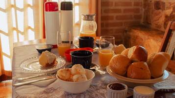 A breakfast setting with bread rolls, butter, jam, and coffee cups on a table.