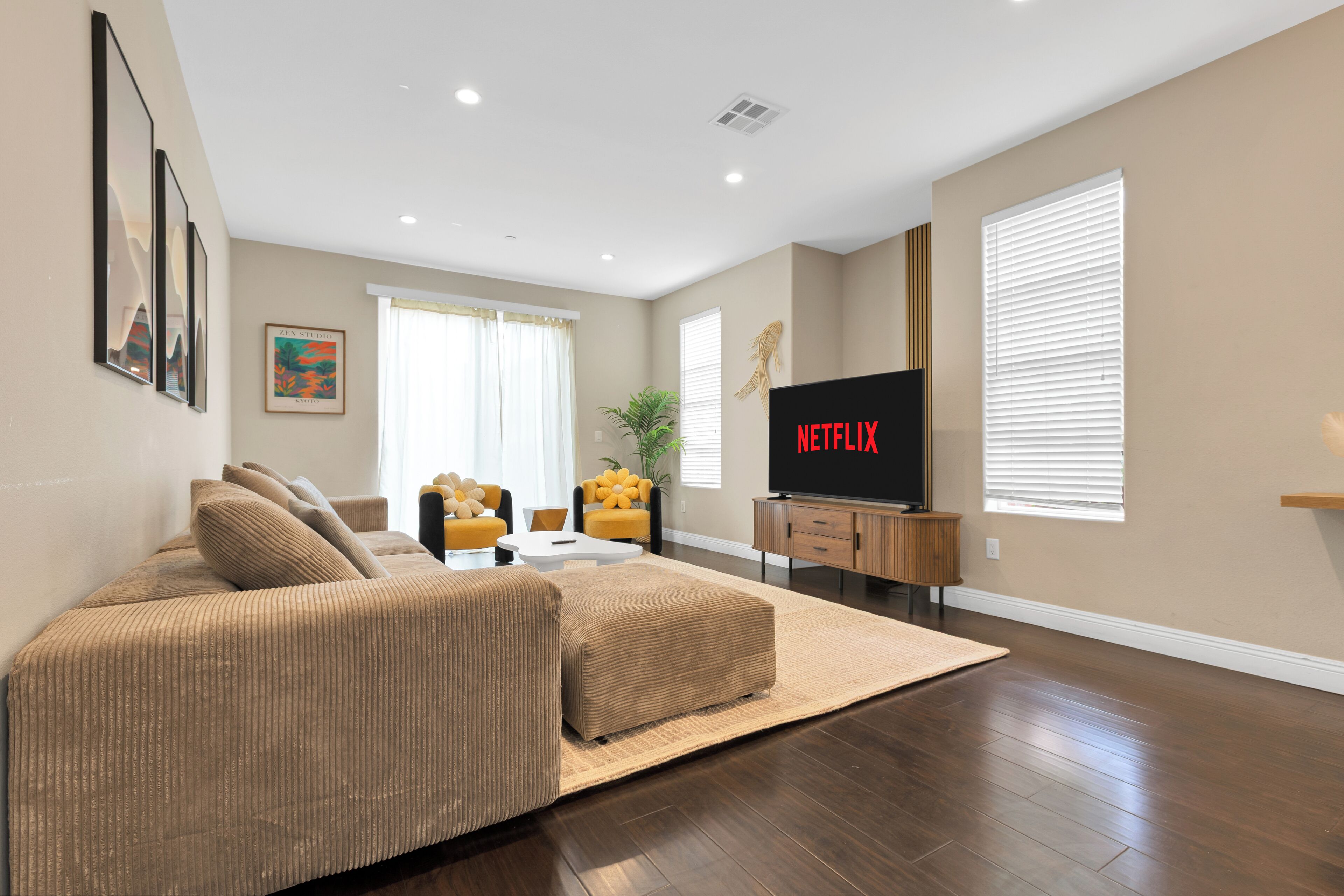 Una sala de estar moderna con un televisor de pantalla plana grande, un sofá y una mesa de centro.