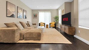 Uma sala de estar moderna com um sofá seccional grande, uma TV de tela plana e uma mesa de centro.