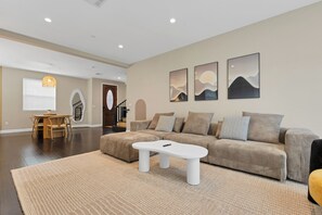 A modern living room with a sectional sofa, a white coffee table, and artwork on the walls. - Prime Location - Spacious 3BD 2.5 BA - King Bed - 2,100+ sq feet (San Gabriel)