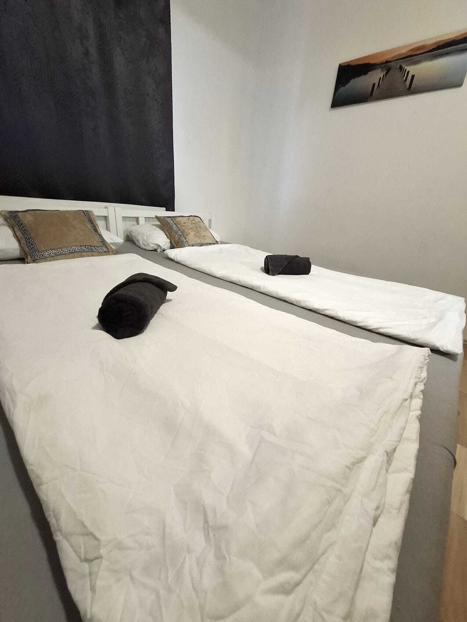 Un letto singolo con biancheria da letto bianca, una borsa nera e un cuscino a motivi geometrici.