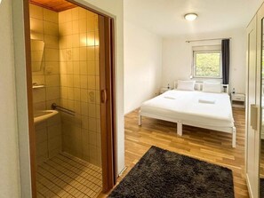 A bedroom with a bed, a window, a shower, and a wooden floor. - Adelin Vienna (Vienna)