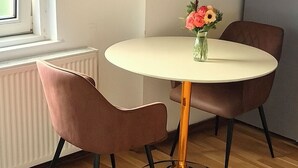 En matplats med ett runt bord, två stolar, en vas med blommor och ett skåp med hyllor.