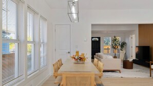 A modern living room with a large TV, a sofa, and a dining area with a table and chairs. - Modern Seattle Retreat 4BR Home Near Downtown (Seattle)