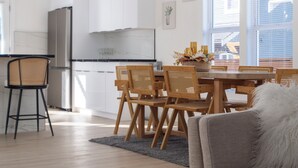 A modern kitchen with white cabinets, a dining area with wooden chairs, and a grey sofa in the living room. - Modern Seattle Retreat 4BR Home Near Downtown (Seattle)