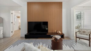 A modern living room with a large flat-screen TV, wooden panel wall, and a comfortable seating area with a sofa and armchair. - Modern Seattle Retreat 4BR Home Near Downtown (Seattle)