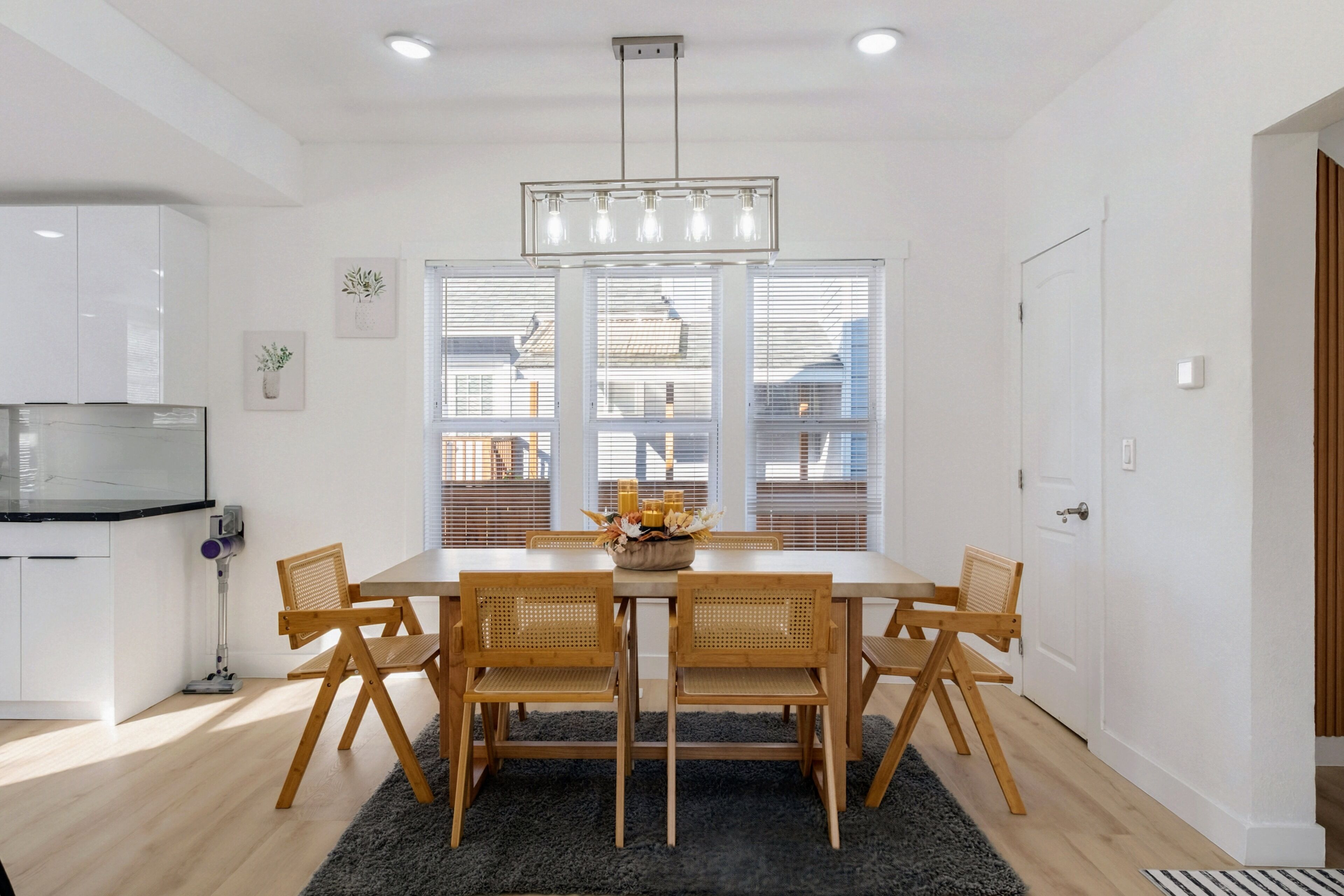 A dining area with a white table, wooden chairs, and a chandelier.