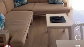 A modern living room with a beige sofa, a small table, and a painting on the wall.