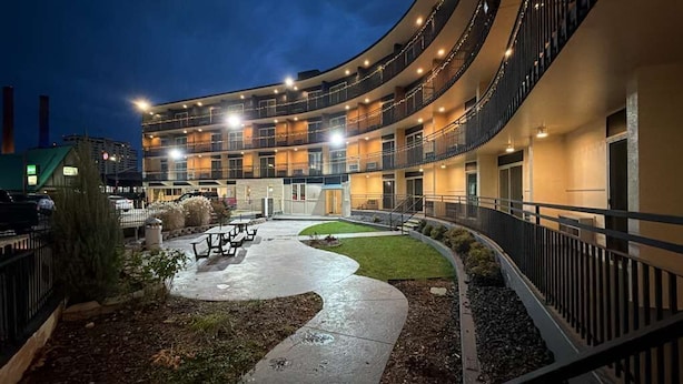 A multi-story hotel with a curved exterior, outdoor seating area, and a well-lit courtyard. - Spokane Boutique Hotel (Spokane)