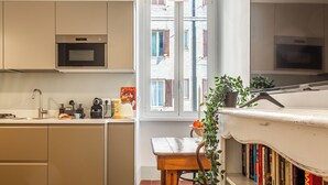 Una cocina moderna con armarios color crema, horno empotrado y ventana con vista a la calle.