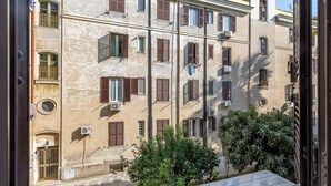 Un edificio de varios pisos con fachada color beige, múltiples ventanas con contraventanas marrones y unidades de aire acondicionado.