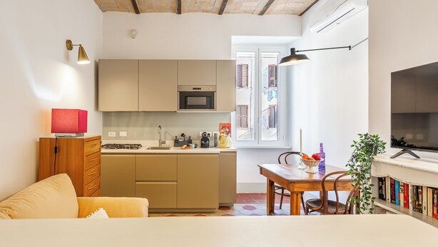 Un espacio habitable compacto con kitchenette, comedor y televisor.