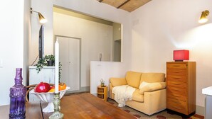 Una sala de estar con una mesa de madera, un sofá, un aparador y una mesita auxiliar con una planta.