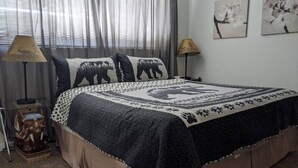 A bedroom with a bed, two lamps, a decorative chair, and artwork on the wall.