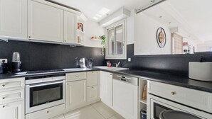 A modern kitchen with white cabinetry, a black countertop, and a built-in oven. - Appartement Margot - Welkeys (Le Cannet)