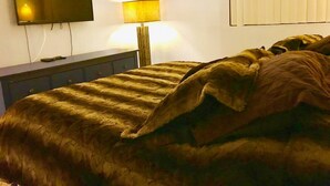 Une chambre à coucher avec un lit, un téléviseur fixé au mur et une lampe de chevet.