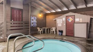 Un espace piscine avec une échelle en métal, une porte rouge et une petite table avec des chaises.
